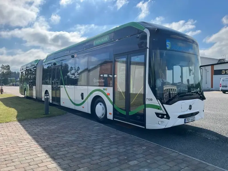Ny Volvo elbuss parkerad på depå, vit med grön dekor.